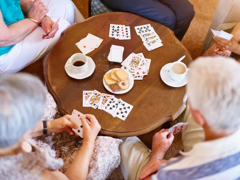 High angle shot of a group of seniors playing cards around a table in their retirement home.