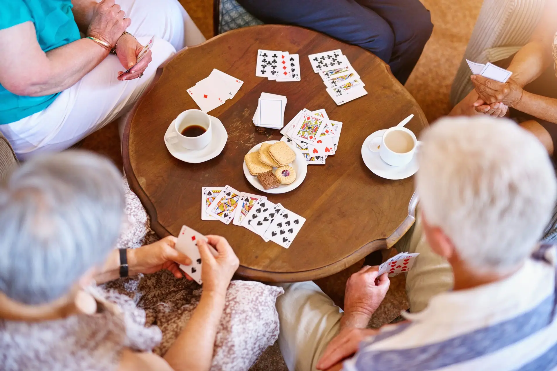 High angle shot of a group of seniors playing cards around a table in their retirement home.